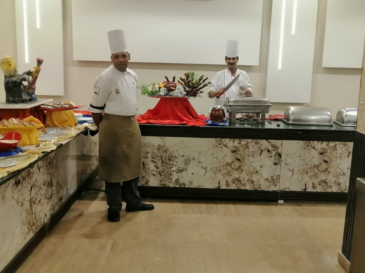 A buffet setup with a marble counter, a red cloth, and various food items.