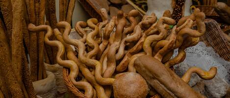 A basket filled with various types of bread, including baguettes and rolls, placed on a table.