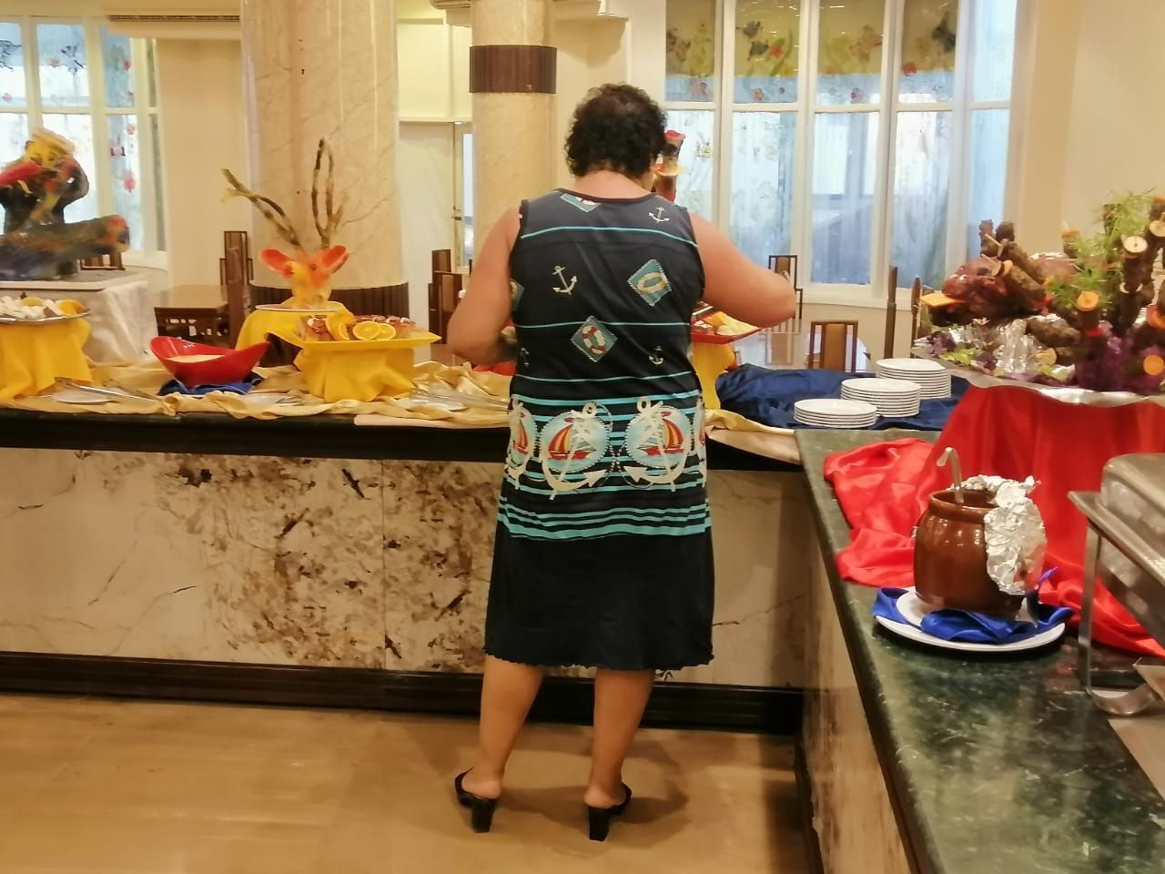 Una persona sirviendo comida en un bufé con diferentes platos y decoraciones.