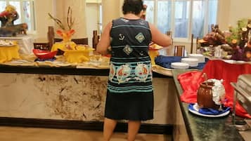 Una persona sirviendo comida en un bufé con diferentes platos y decoraciones.