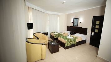 A hotel room with a bed, a chair, a bedside table, and a TV.