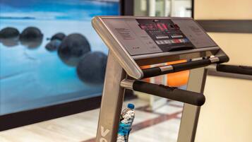 A treadmill with a digital display and a water bottle attached to its frame.