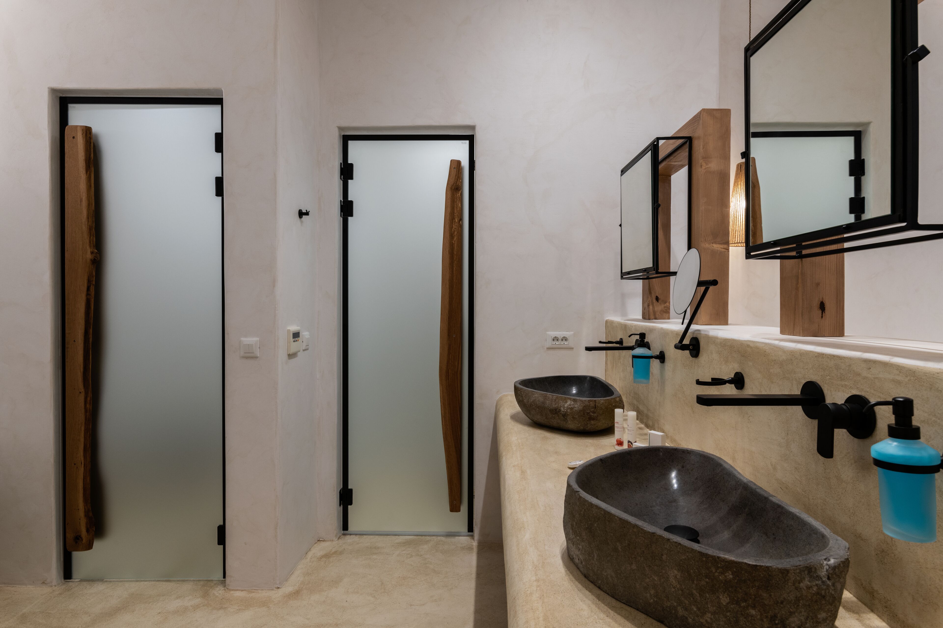 A bathroom with a large stone sink, wooden doors, and a mirror with a wooden frame.
