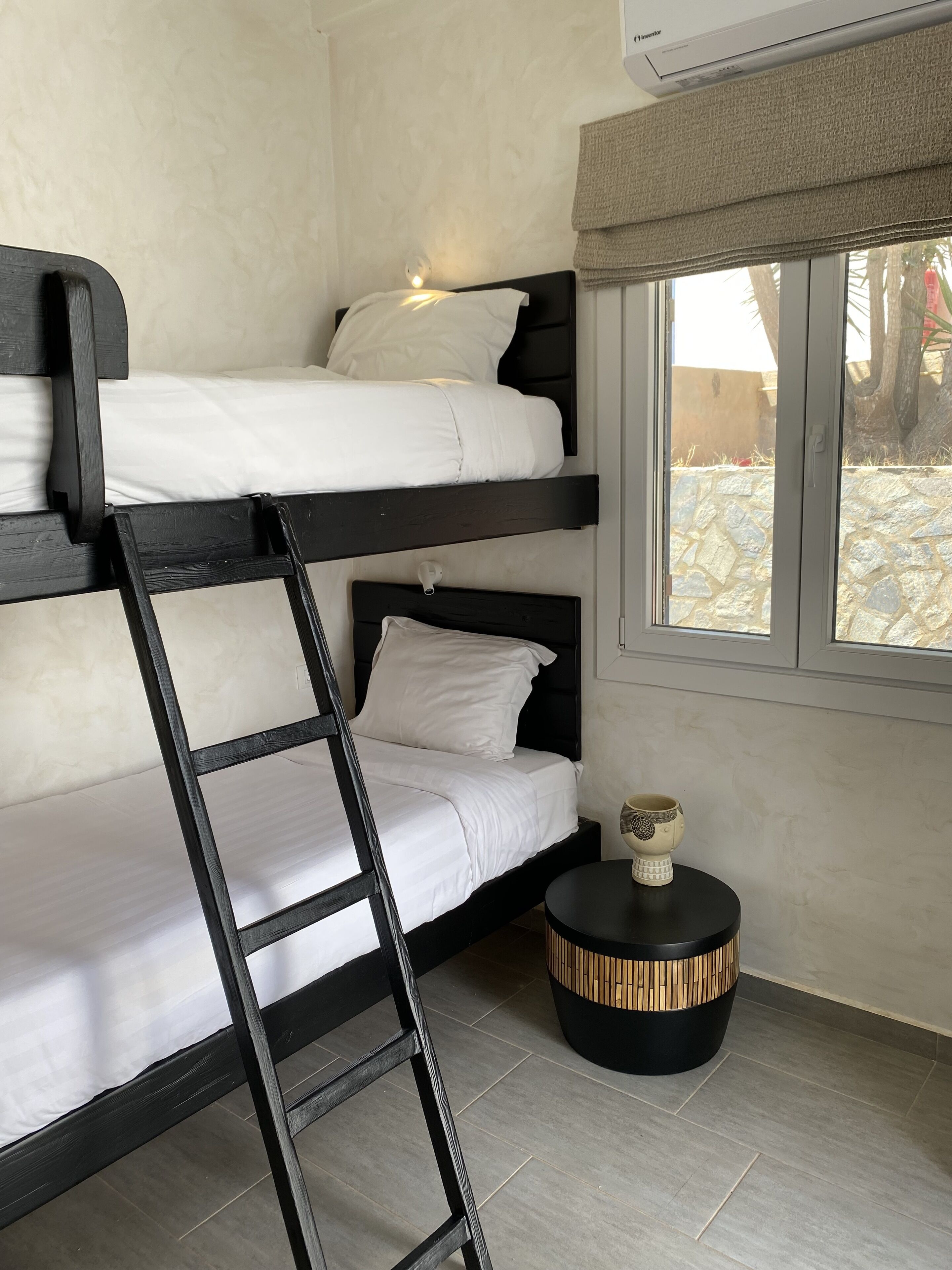 Habitación con literas, una mesa redonda con un objeto decorativo y una ventana con vistas al exterior.