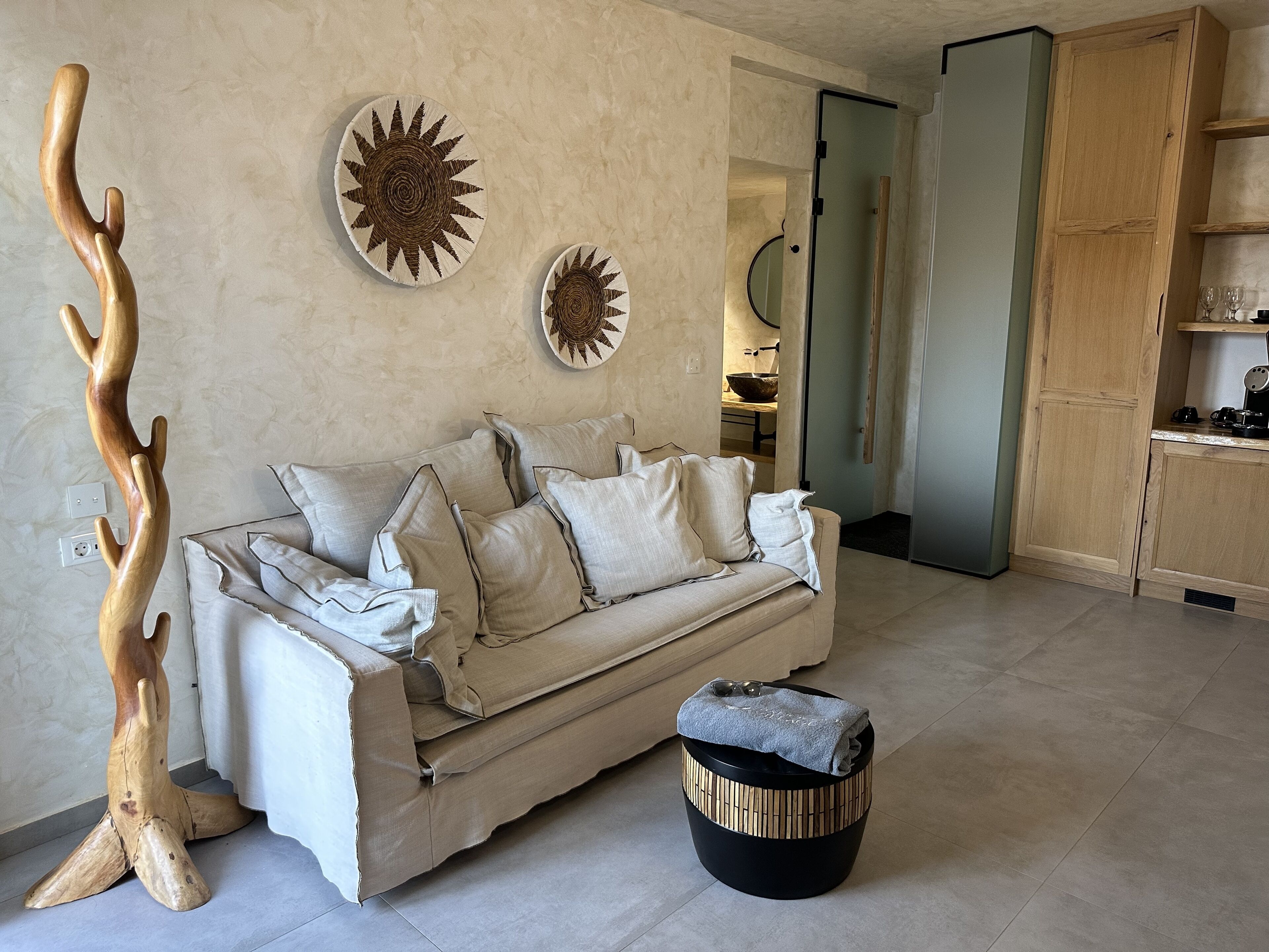 Un salon comprenant un canapé, une table ronde en bois et deux éléments de décoration murale.