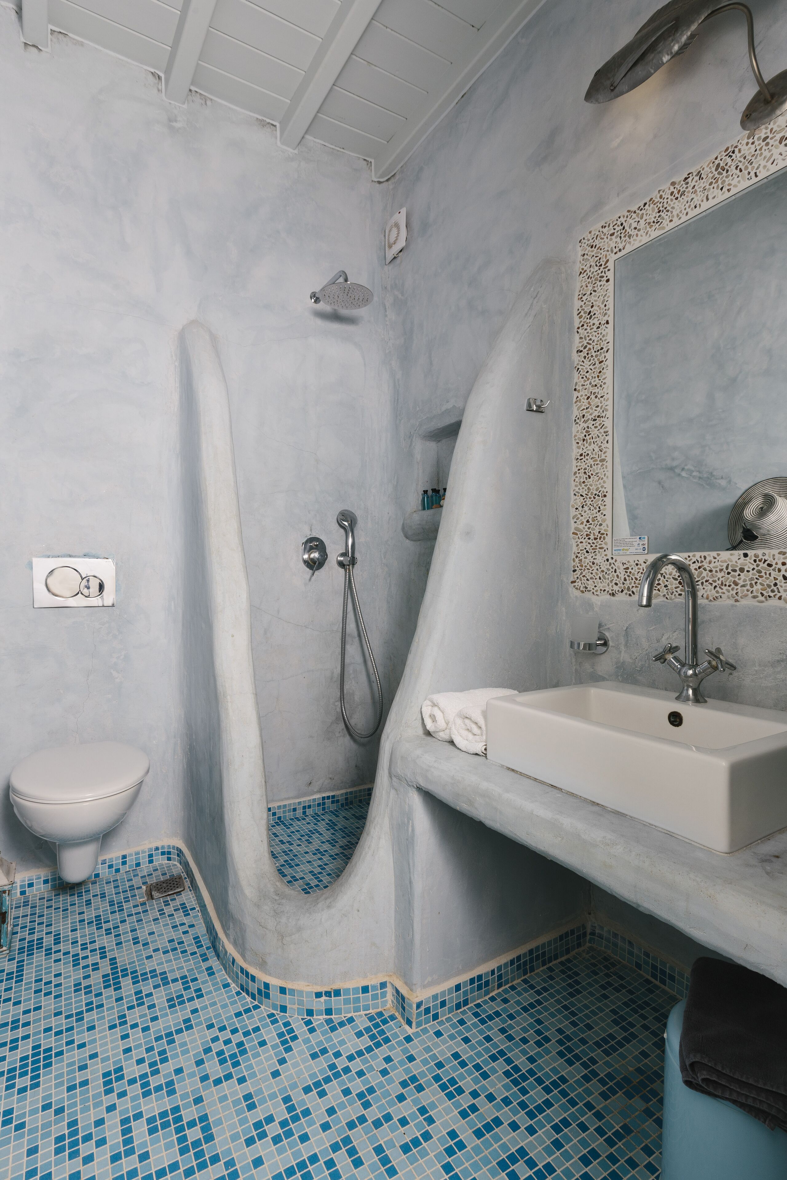 Baño con ducha, inodoro, lavamanos y espejo con marco decorativo.