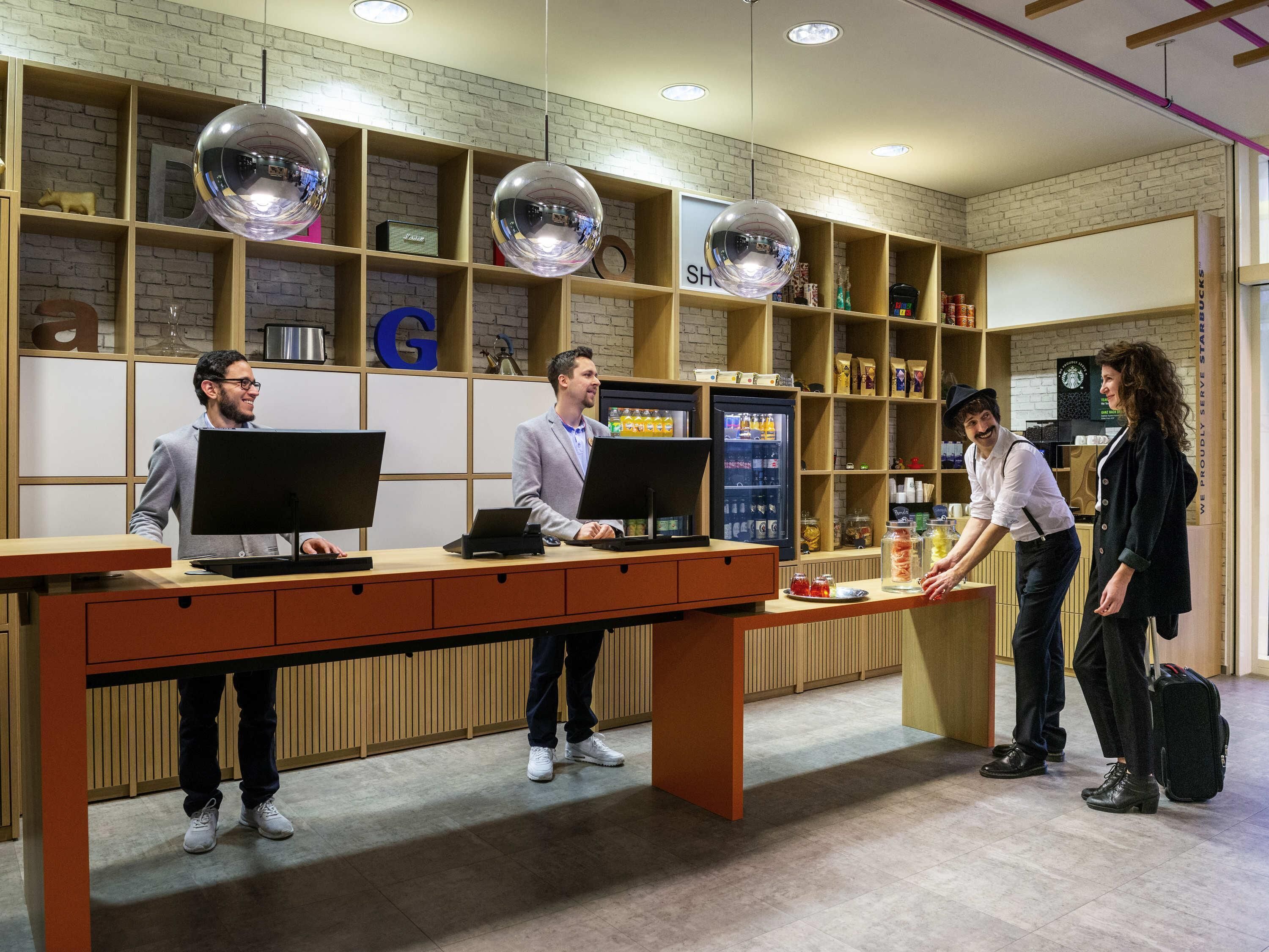 A reception desk with three employees, a coffee machine, and shelves with various items.