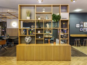 A modern reception desk with a wooden finish, surrounded by shelves with various decorative items and a 'LIBRARY' sign.