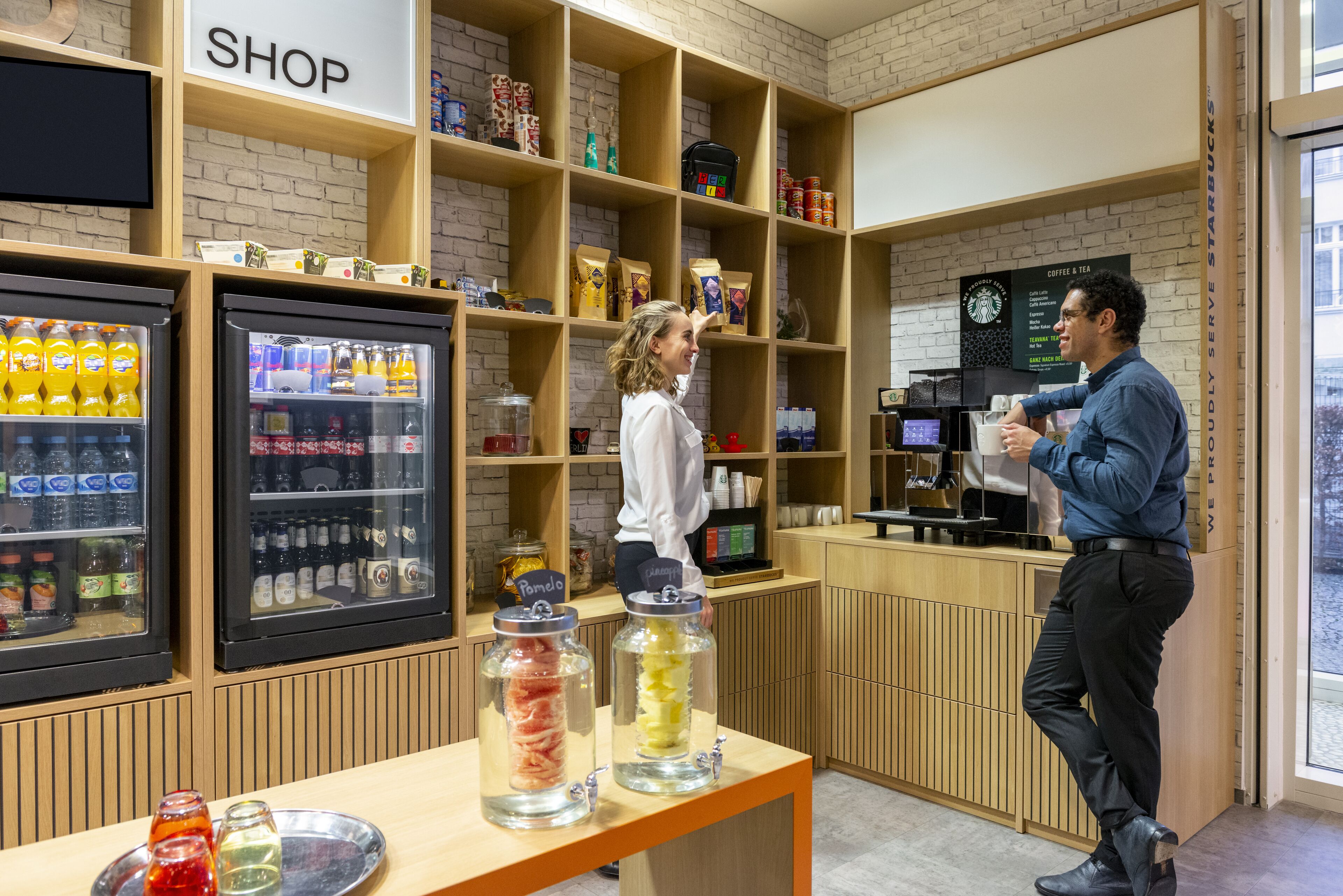 Interior de una cafetería con estanterías llenas de granos de café y una exhibición de bebidas embotelladas.