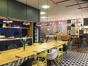 Un comedor moderno con una larga mesa de madera, sillas amarillas y un tapete con diseño blanco y negro.