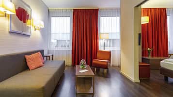 Ett hotellrum med en soffa, en fåtölj och ett litet bord med en vas.