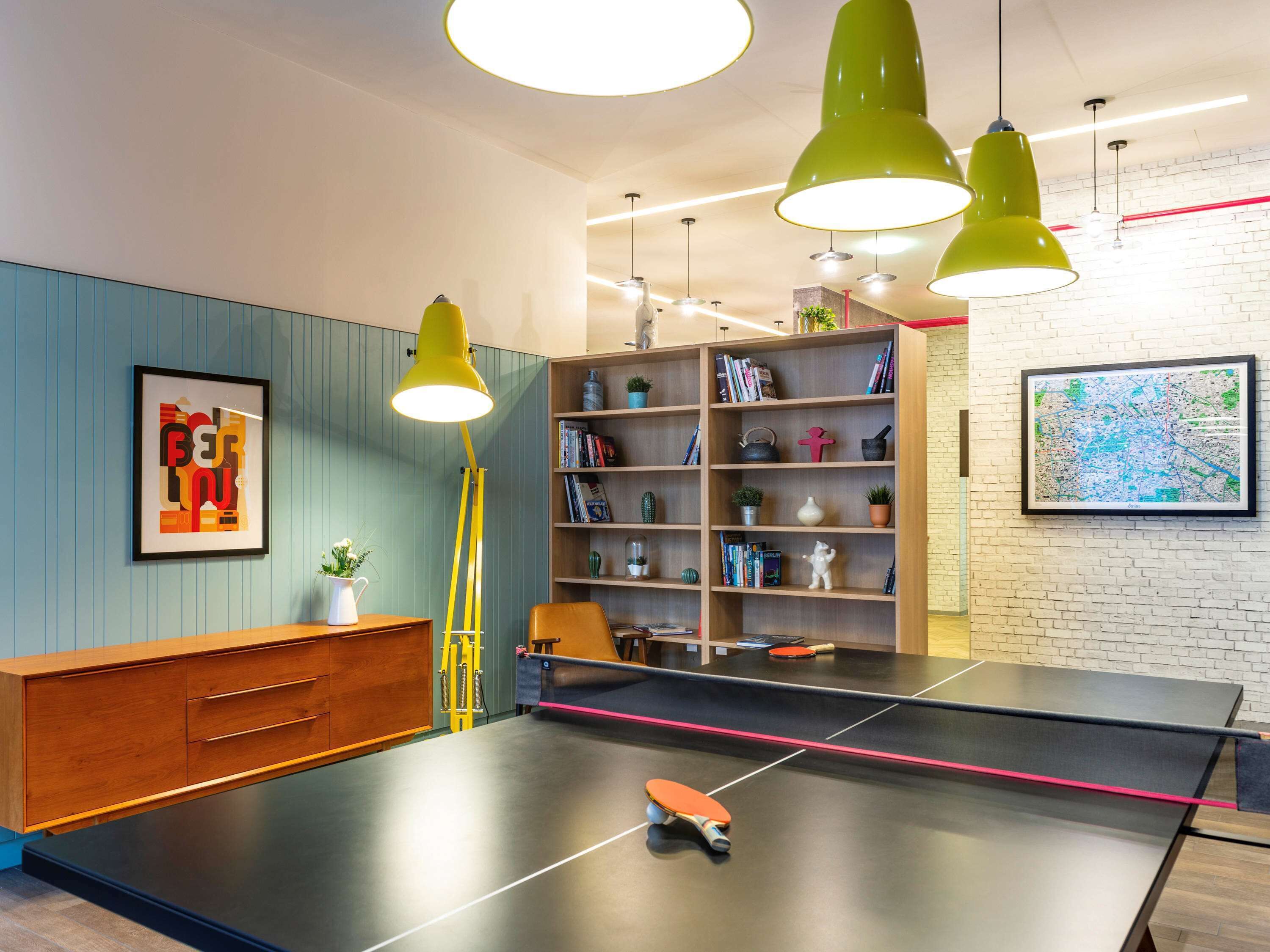 A ping pong table with a table tennis paddle, a bookshelf, and a map on the wall.