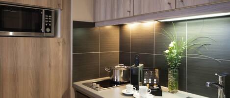 A modern kitchen with wooden cabinets, a stainless steel sink, a microwave, and a coffee machine.