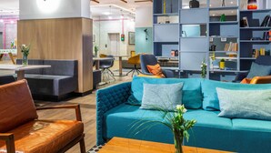 Ein moderner Lounge-Bereich mit einem türkisfarbenen Sofa, Ledersesseln und einem Holztisch.