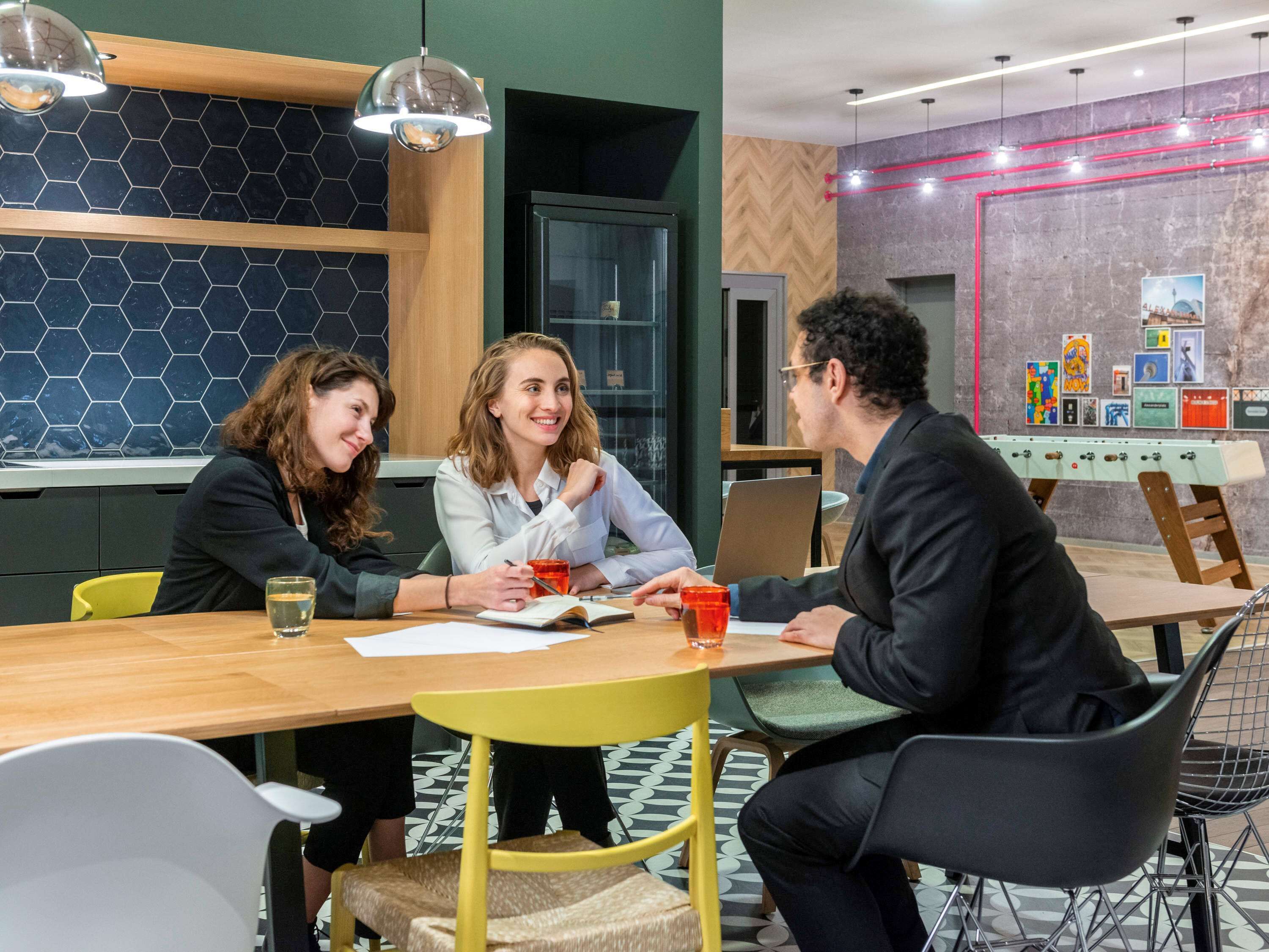 Een moderne vergaderruimte met een houten tafel, gele stoelen en een glazen scheidingswand.