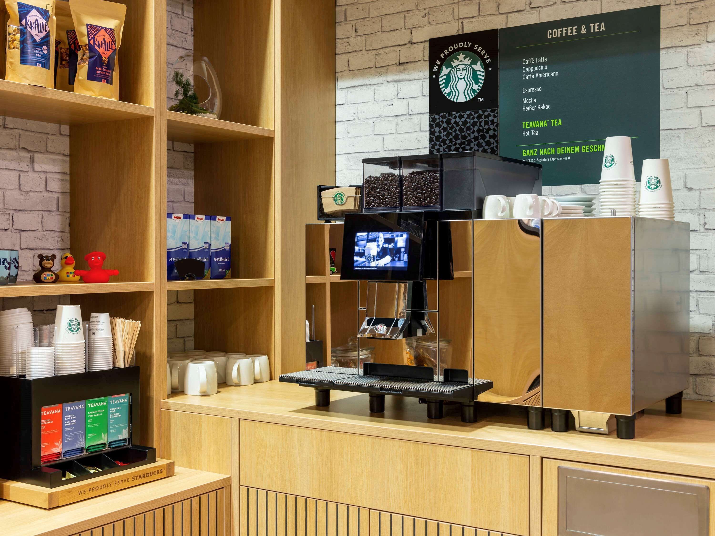 A coffee shop counter with a Starbucks coffee machine, a menu board, and various coffee products on shelves.