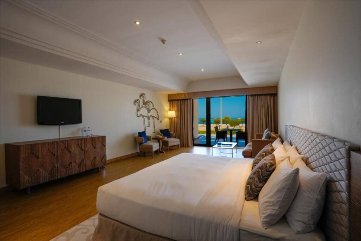 Una habitación de hotel moderna con una cama grande, un televisor de pantalla plana, un mueble de madera y un balcón con vistas.