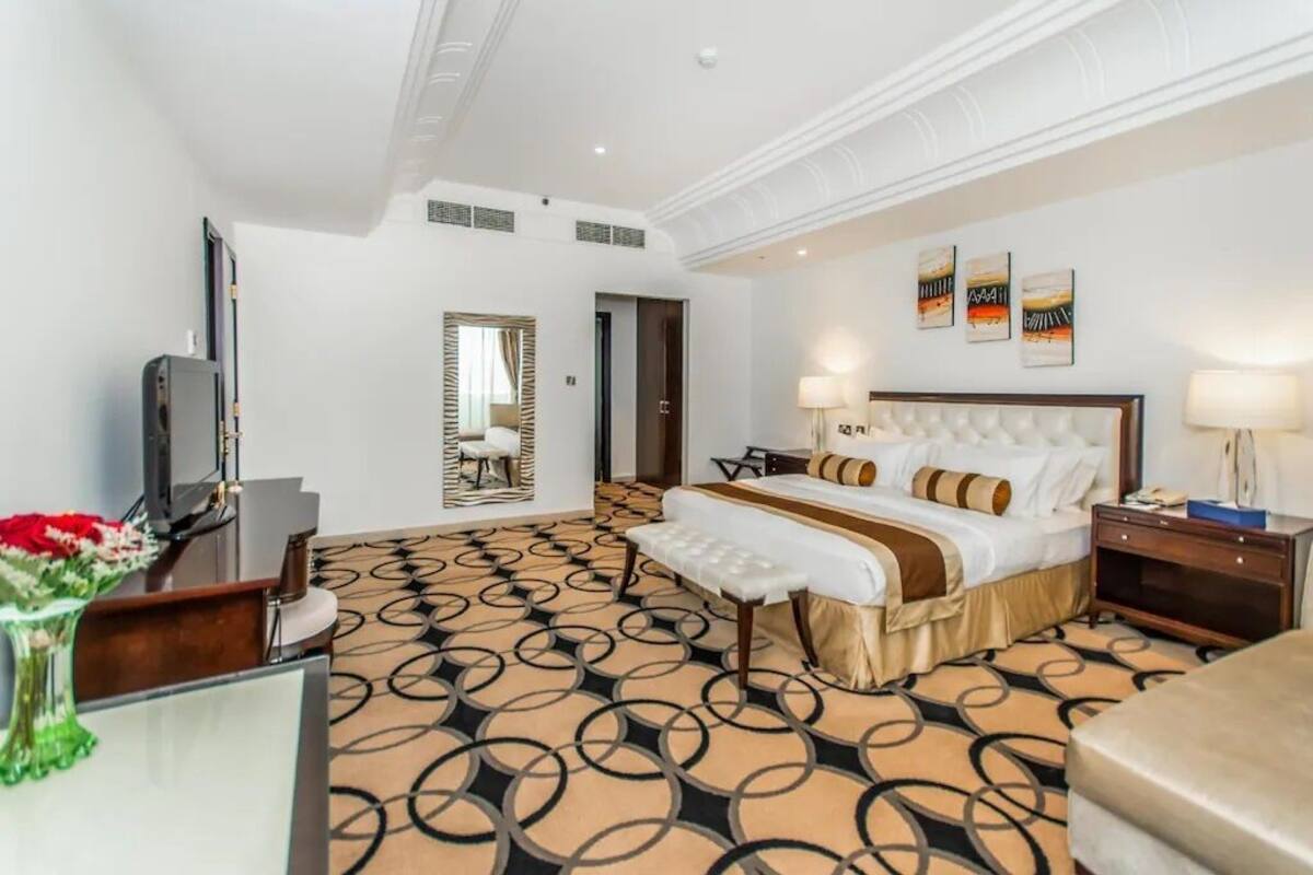 Una habitación de hotel con una cama grande, un escritorio, un televisor y un espejo.