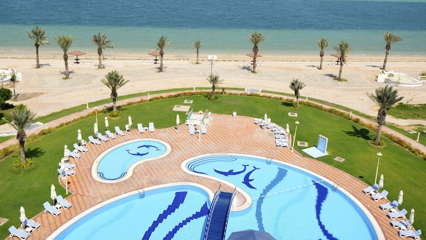 Un resort con un amplio área de piscina, playa y vistas al océano.