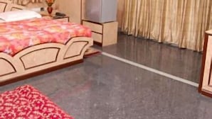 A bedroom with a bed, a TV, and curtains. - Hotel Suriya International (Chennai)