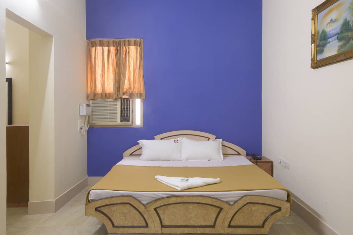 Un dormitorio con cama, ventana con cortinas, un cuadro en la pared y una mesita de noche.