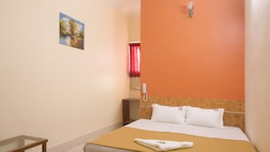 A hotel room with a bed, a bedside table, a telephone, and a painting on the wall. - Hotel Suriya International (Chennai)