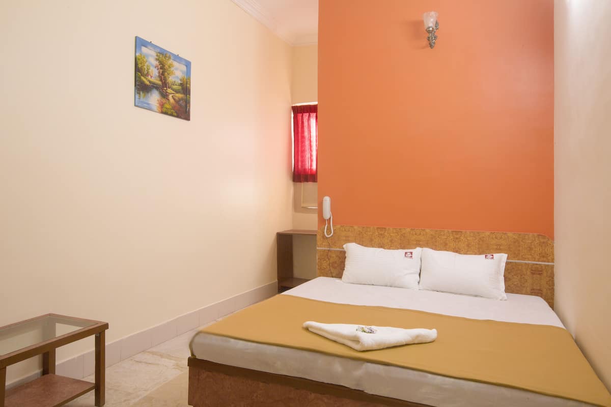 Una habitación de hotel con una cama, una mesita de noche, un teléfono y un cuadro en la pared.