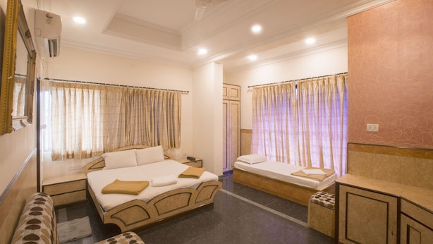 A hotel room with a large bed, a smaller bed, a bench, and a desk. - Hotel Suriya International (Chennai)