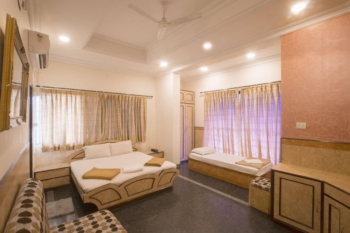 Una habitación de hotel con una cama grande, una cama más pequeña, un banco y un escritorio.