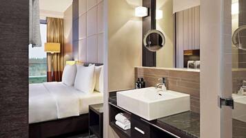 Habitación de hotel con una cama grande, baño con lavamanos y espejo, y vista al exterior.