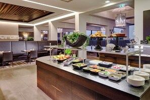 Zona de bufé con diversas opciones de comida, arreglos de asientos y un diseño interior moderno.