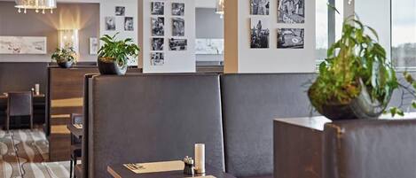 Un moderno vestíbulo de hotel con asientos de cuero, una alfombra estampada y fotografías blanco y negro colgadas en la pared.