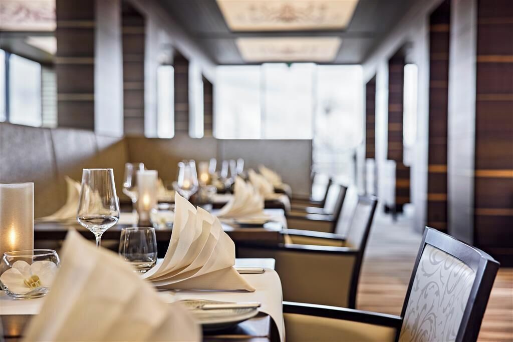 Un restaurante con mesas largas dispuestas para comer, con velas y servilletas dobladas.