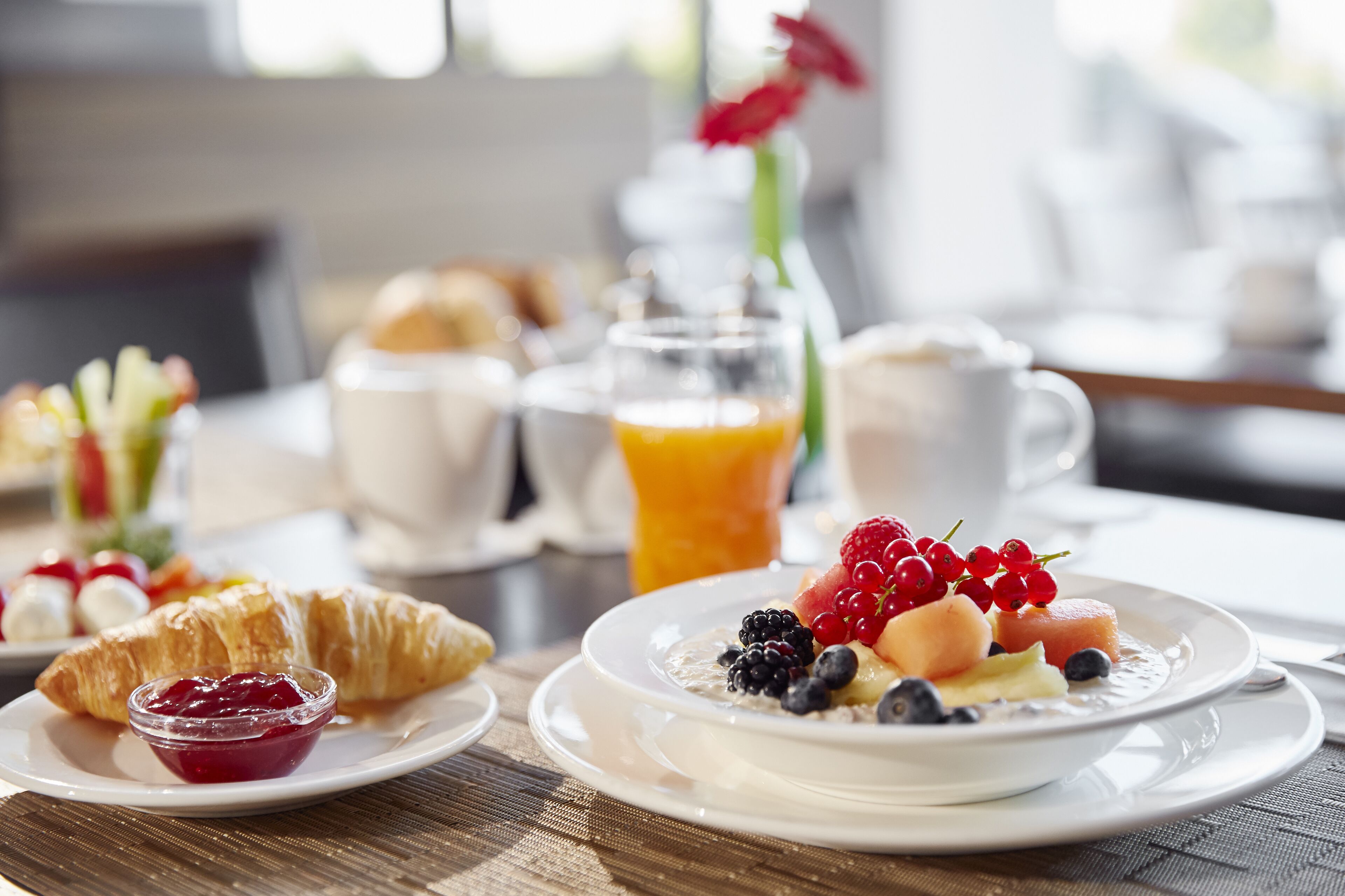 A breakfast setting with croissants, fruit, and a glass of orange juice on a table.
