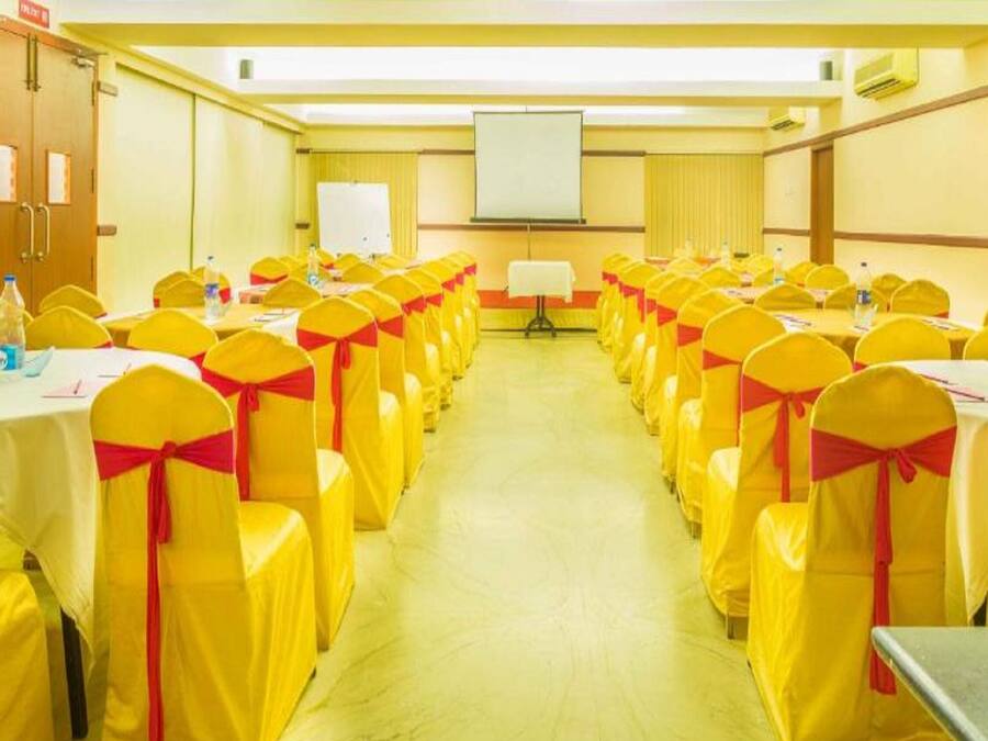 A conference room with rows of tables and chairs, each with yellow chairs tied with red sashes.