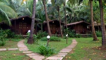 A tropical resort with wooden cabins, a stone pathway, and lush greenery.