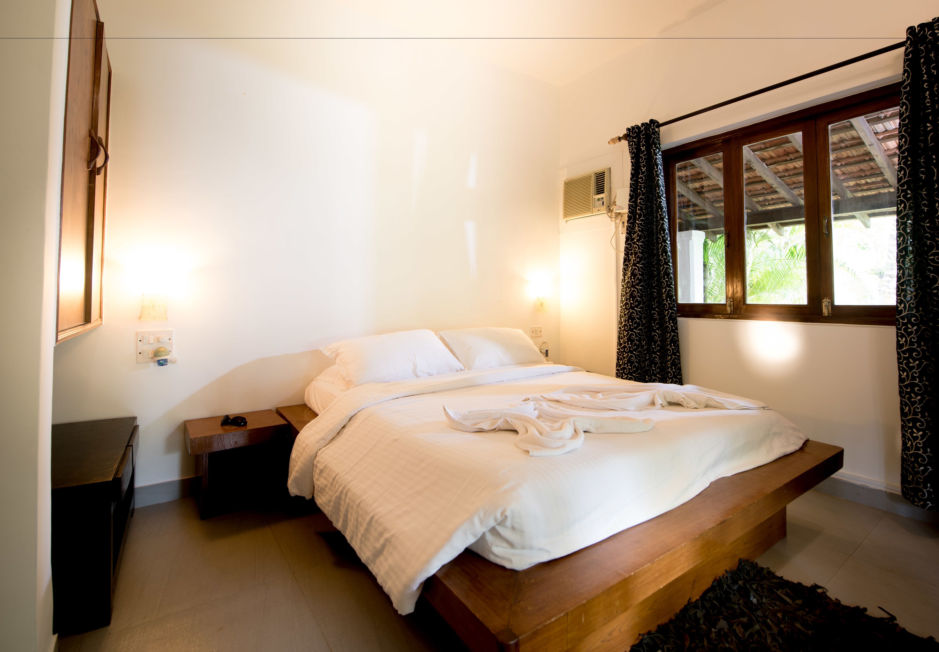 Un dormitorio con cama de madera, mesitas de noche y una ventana con cortinas.