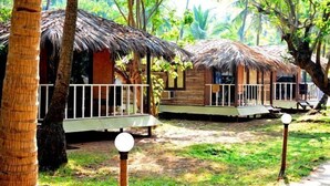 A tropical resort with thatched-roof cabins, a wooden deck, and a lush green environment. - Montego Bay Beach Village (Morjim)