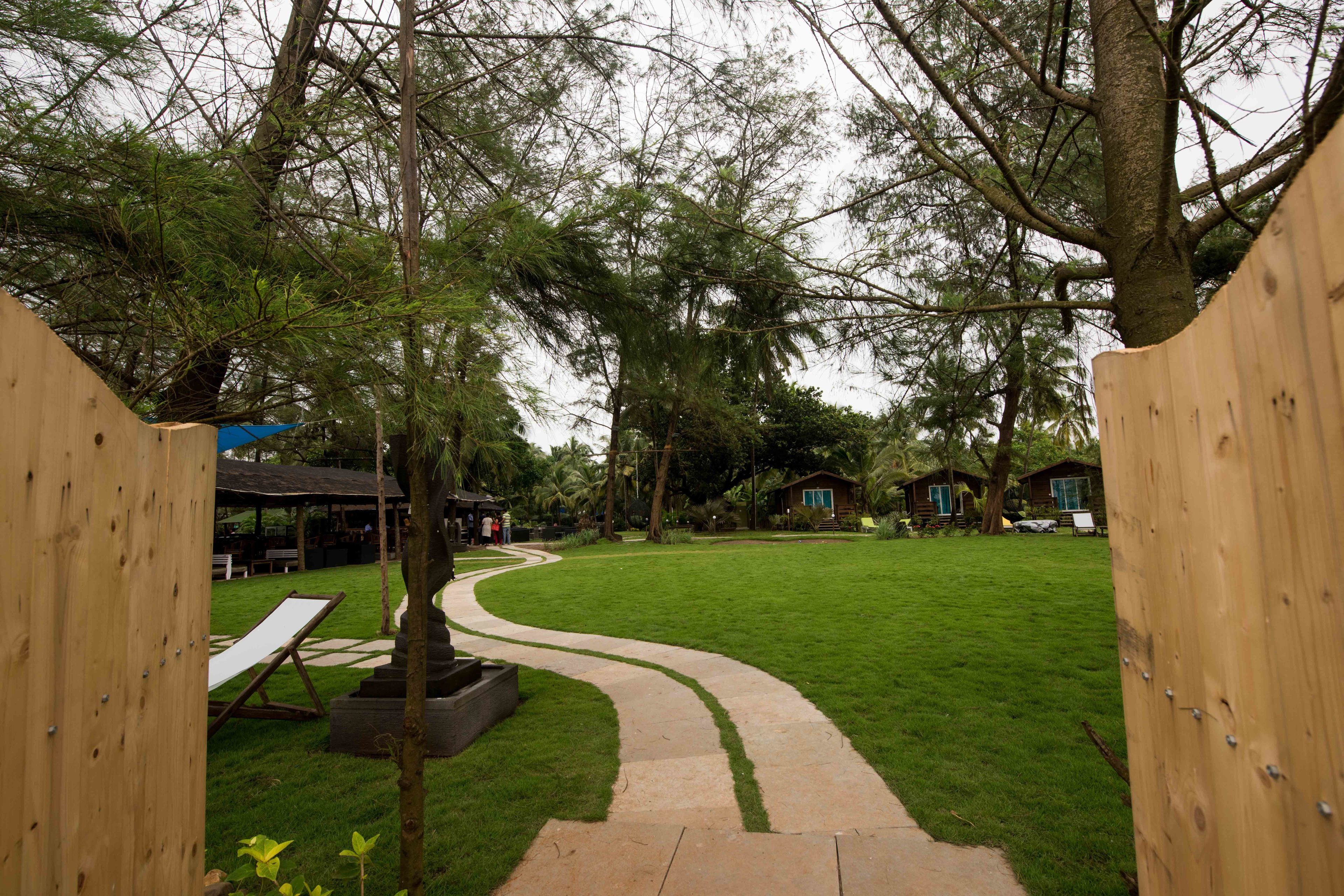Un jardín cuidado con un sendero serpenteante, cercas de madera y una mesa de picnic.