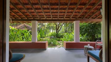 A covered outdoor seating area with a view of a lush garden.