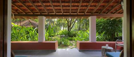 Un espacio de estar techado al aire libre con vistas a un exuberante jardín.