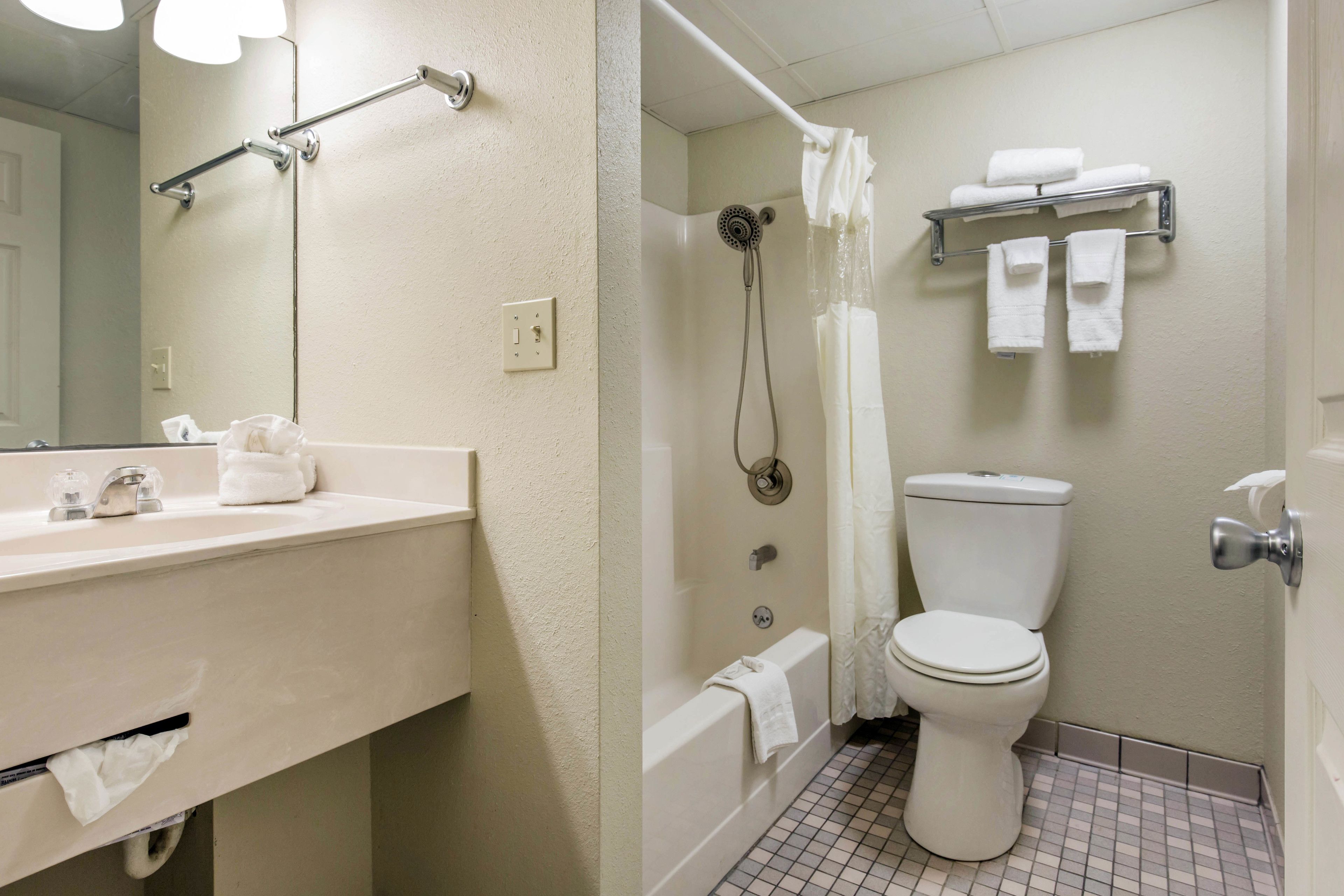 A bathroom with a sink, mirror, shower, toilet, and towel rack.