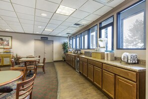 A hotel room with a kitchenette, dining area, and large windows.