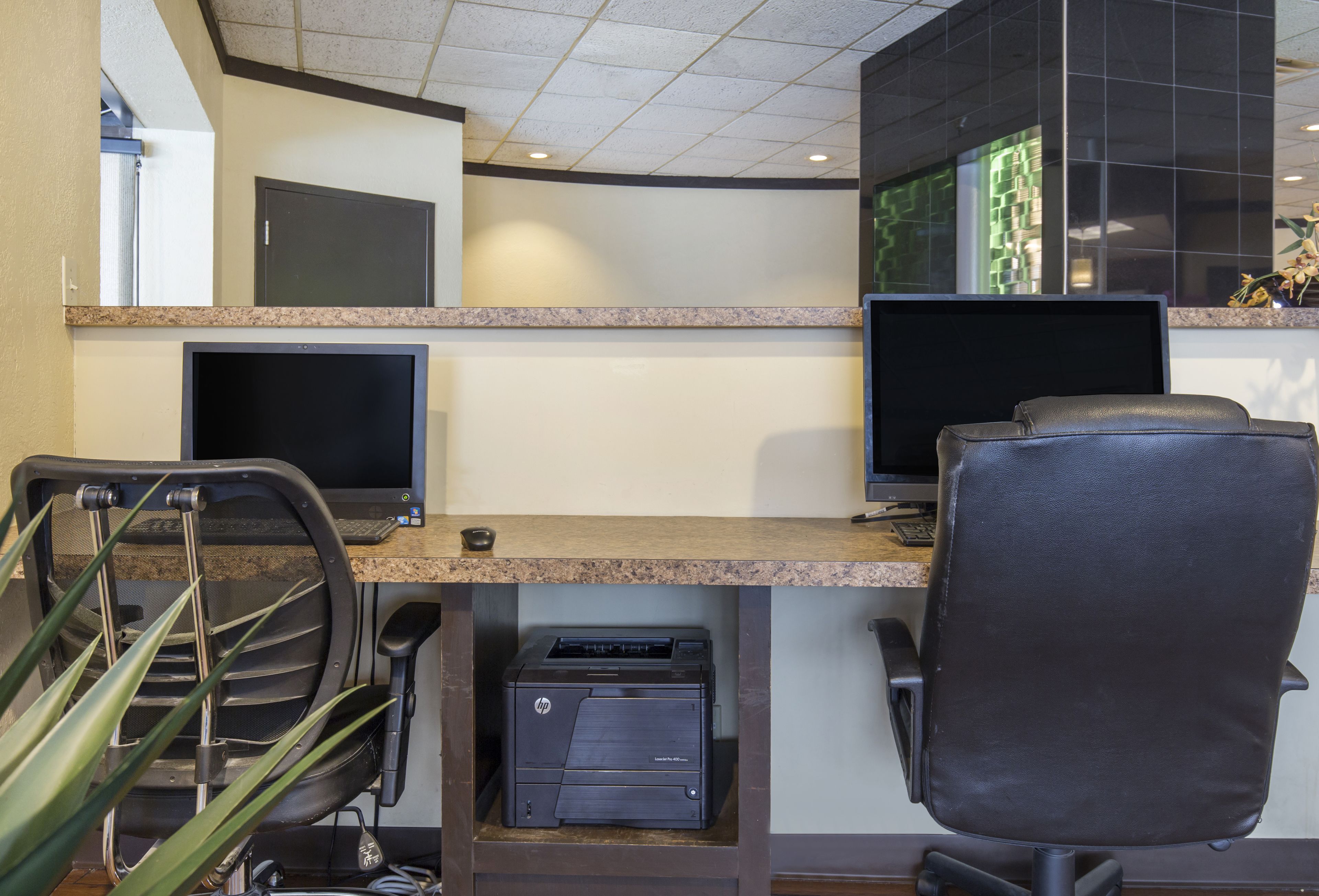 Un espace de travail équipé de deux écrans, d’une imprimante et de chaises de bureau.