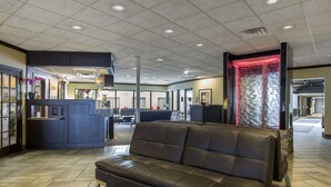 A lobby with a leather sofa, a reception desk, and a stone wall with a red light.