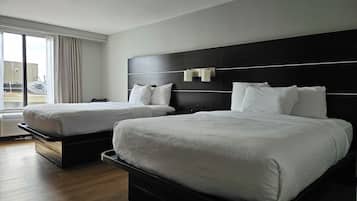 Una habitación de hotel con dos camas, un ventanal con cortinas y vistas al exterior.