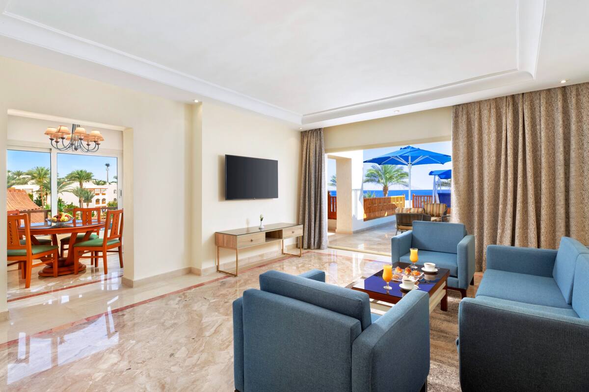 A spacious living room with a large TV, comfortable seating, a dining area, and a view of the outdoors.