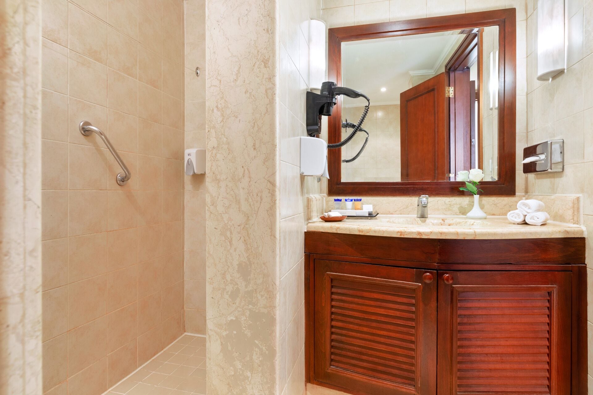 Une salle de bain avec une douche, un meuble-lavabo avec un miroir et un porte-serviettes.