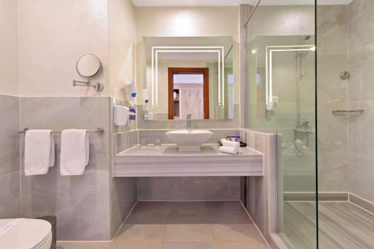 Une salle de bain moderne avec une douche à parois de verre, un lavabo en marbre et un grand miroir.