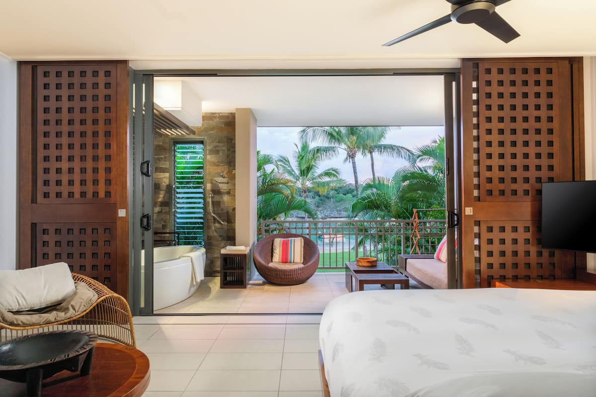 Ein Hotelzimmer mit Balkon, einem Bett, einer Couch und einem Fernseher.